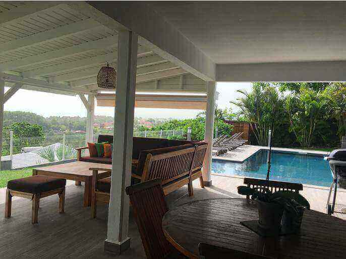 Location VillaMaison en Guadeloupe - Côté terrasse couverte de 50m2 avec carrelage anti-dérapant vue sur la piscine et la mer